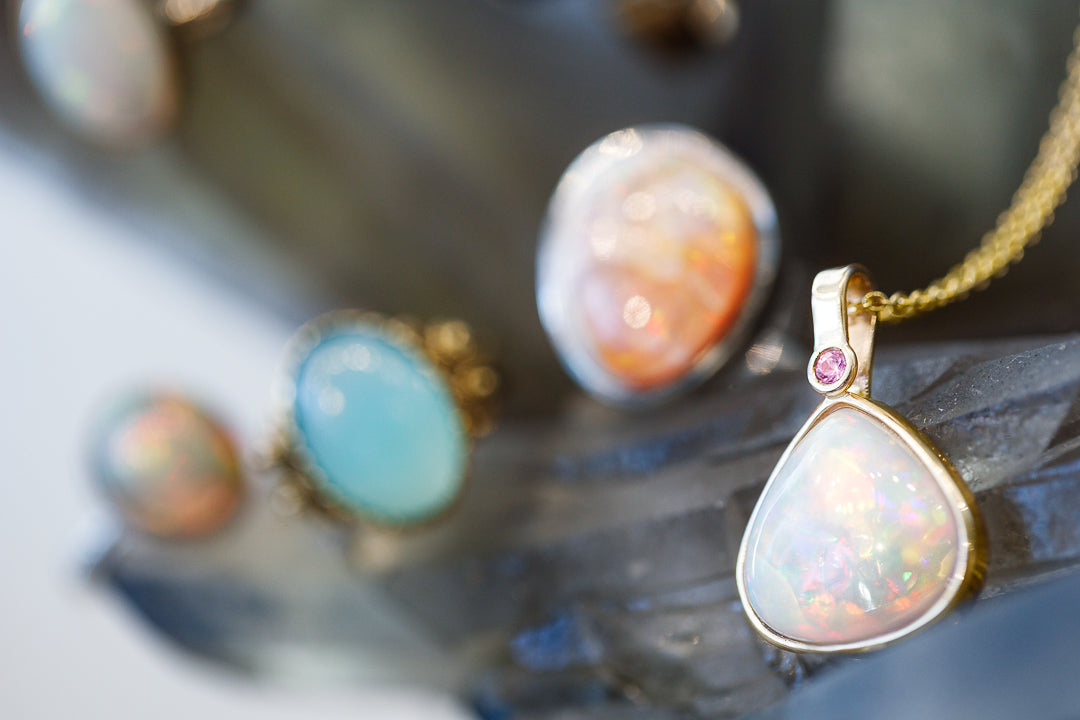 Opal pendant with gold setting on a blurred background