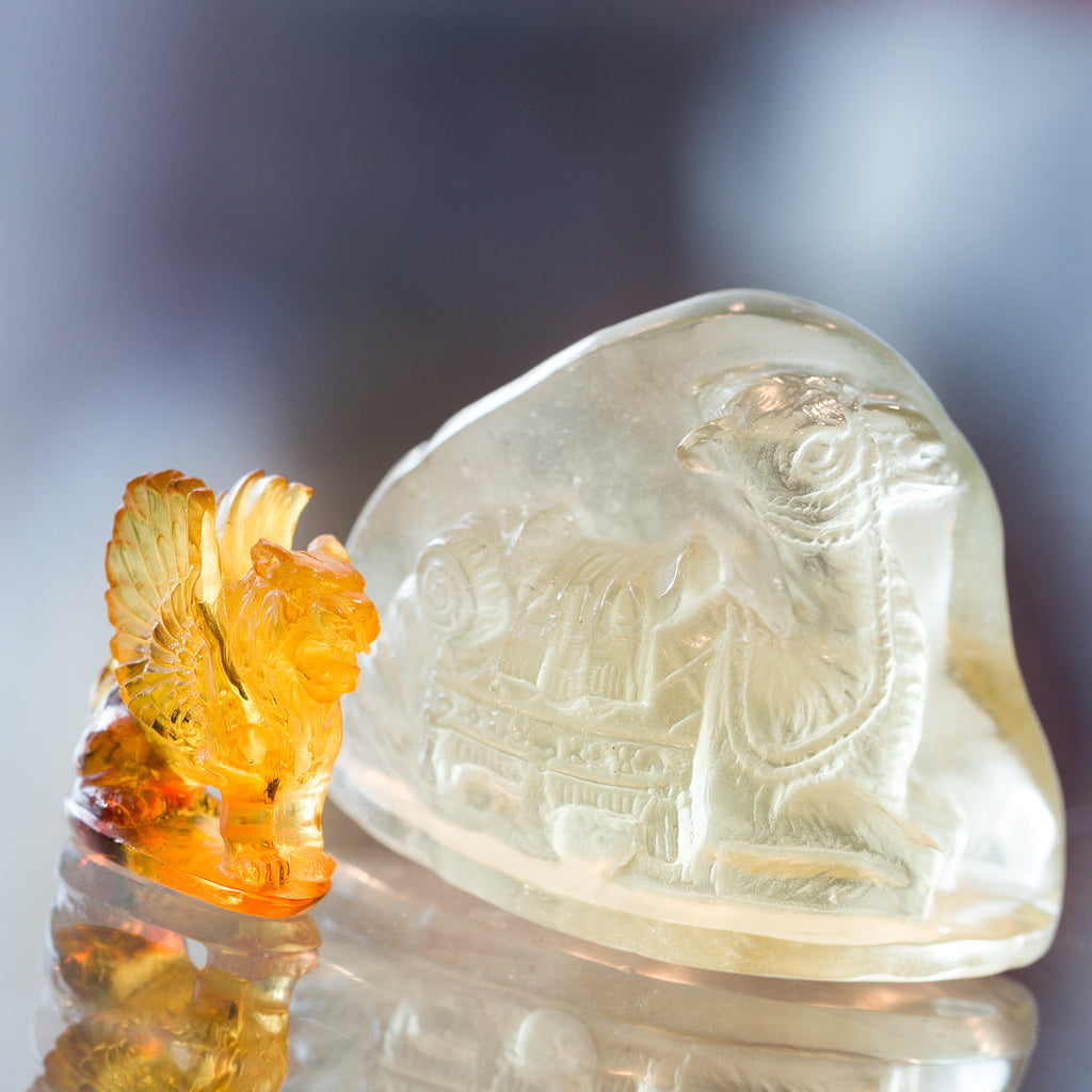A winged lion carved from gem quality amber sits next to a camel carved from soft green libyan desert glass showcasing a new collection of crystal carvings