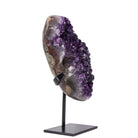 Deep purple Amethyst geode displayed on a black metal stand, angled view
